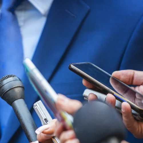 image of news reporters holding microphones and recording devices during an interview